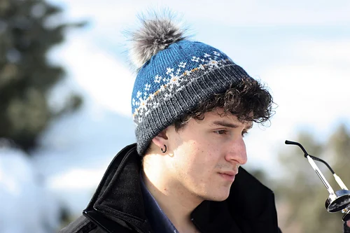 Sierra Snowcap knitted hat by Romi Hill worn by man outdoors, featuring classic snow-inspired design with textured ribbed stitchwork